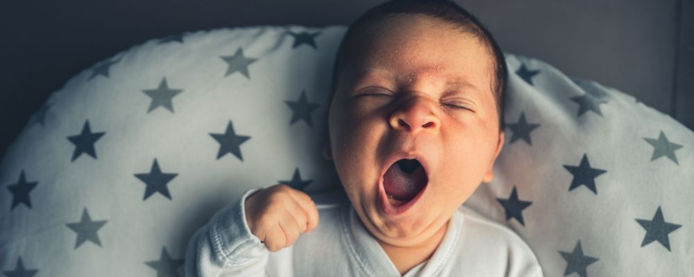 Bebê com a boca aberta se espreguiçando